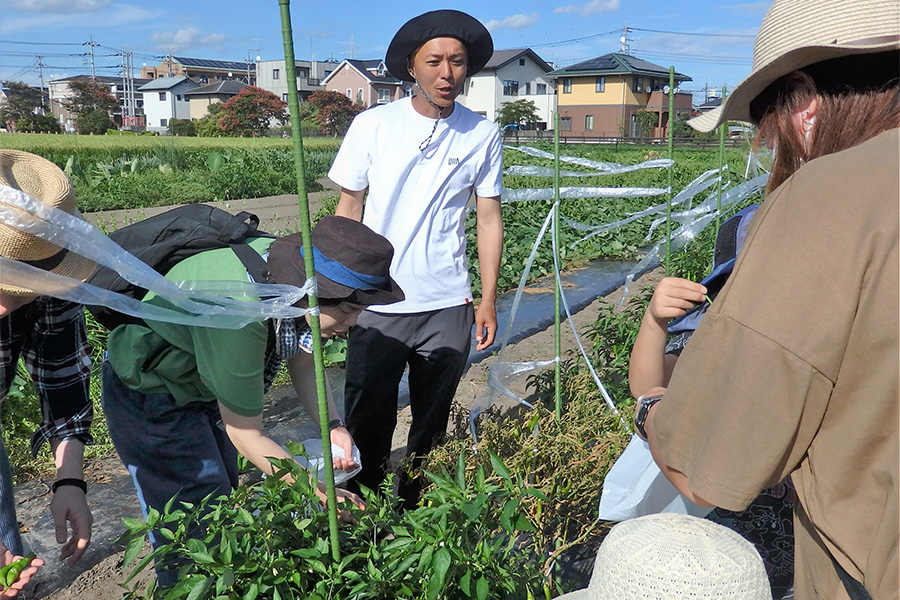 農業体験会に訪れた親子に丁寧に説明する西澤代志也【写真：河野正】