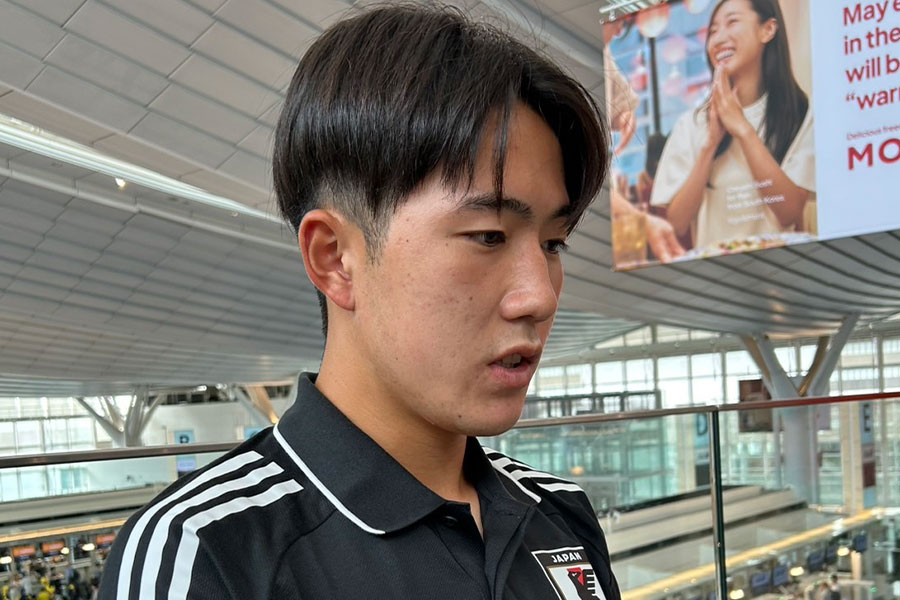 空港で取材対応に応じた佐藤龍之介【写真：FOOTBALL ZONE編集部】