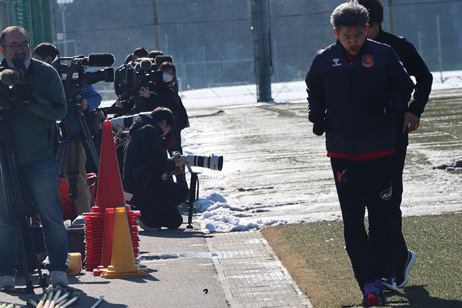 雪の残るピッチをカメラの放列を浴びながら走るカズ【写真：荻島弘一】