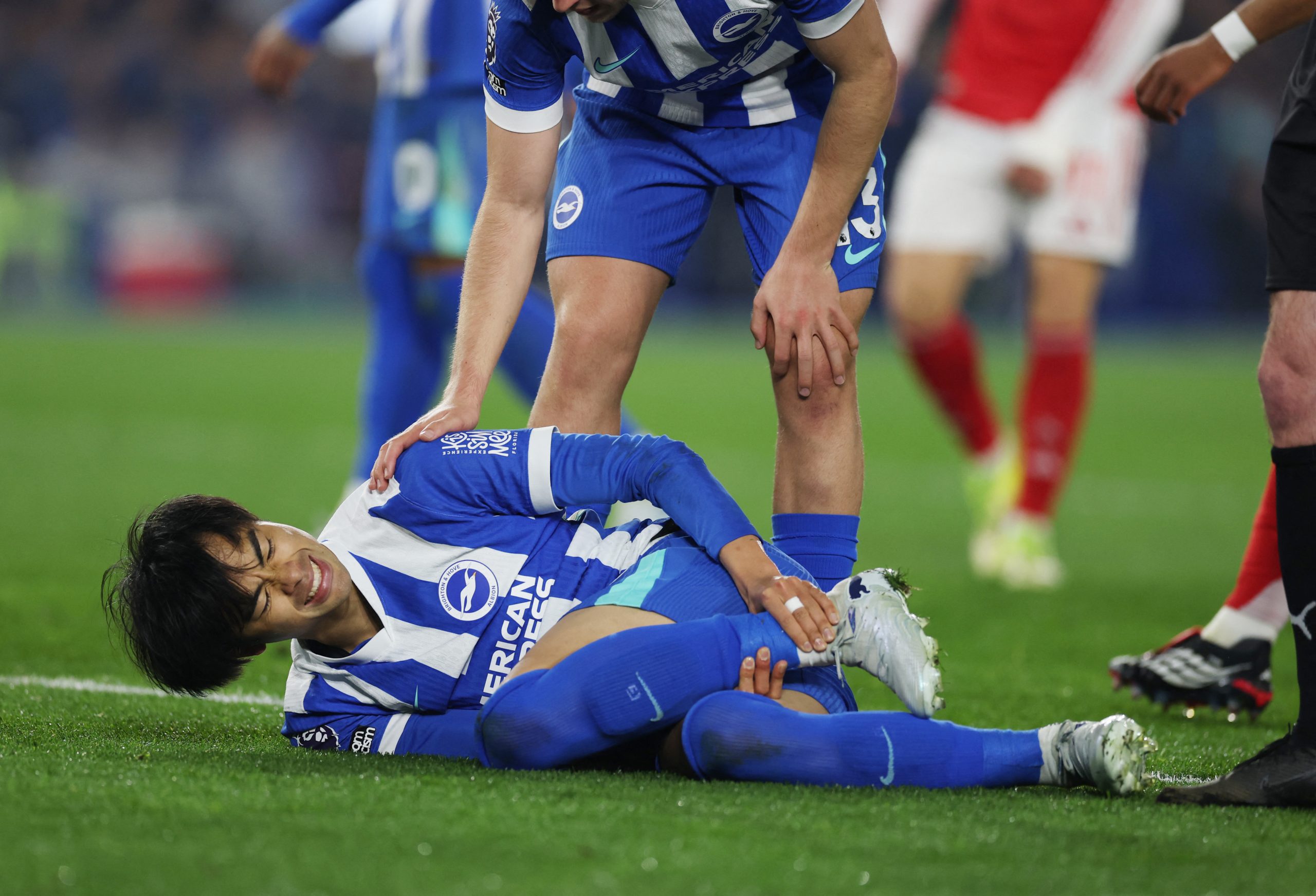 左足首を抑えてうずくまる三笘薫【写真：ロイター/アフロ】